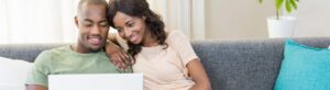 Couple sitting on couch together looking at laptop
